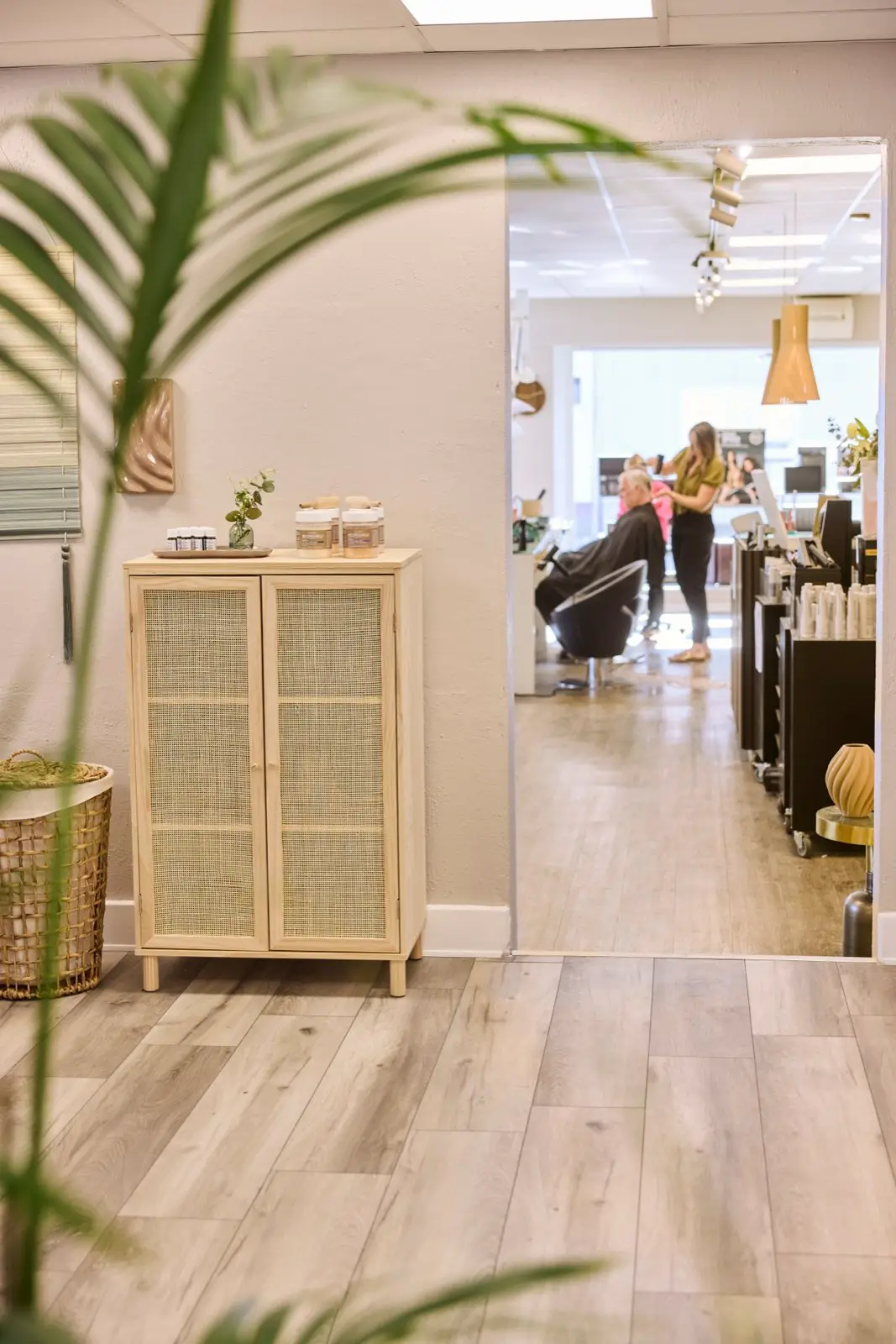 Frisør Lindemark — fletskab med naturmaterialer og kurv i forgrunden, salon i baggrunden